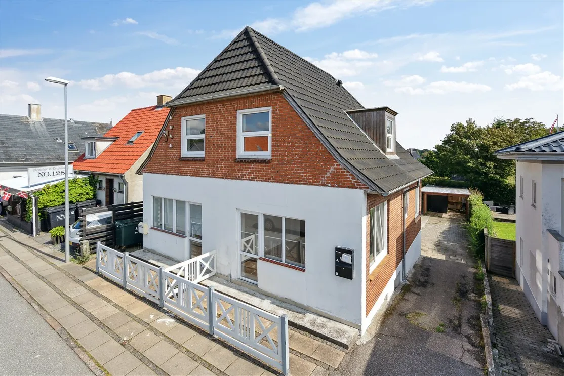 Koldingvej 125, et hvidt og rødt hus med tegltag, vindue med hvidt indrammet og hvide spær. Der er et rødt tag og en hvid