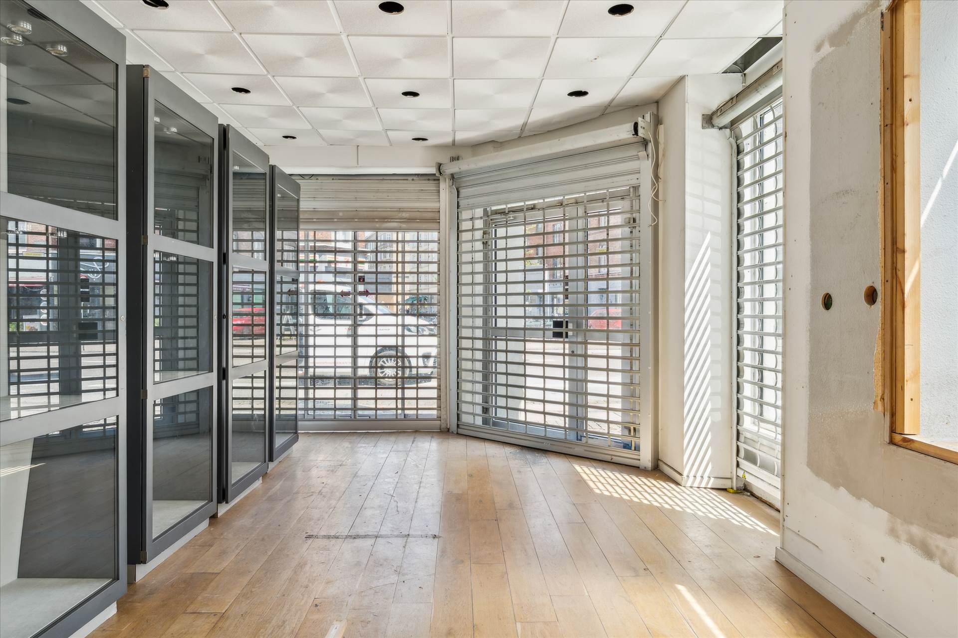 Et erhvervslejemål med hjørneplacering, store ruder og lyse skyggeslag på gulvet og væggene