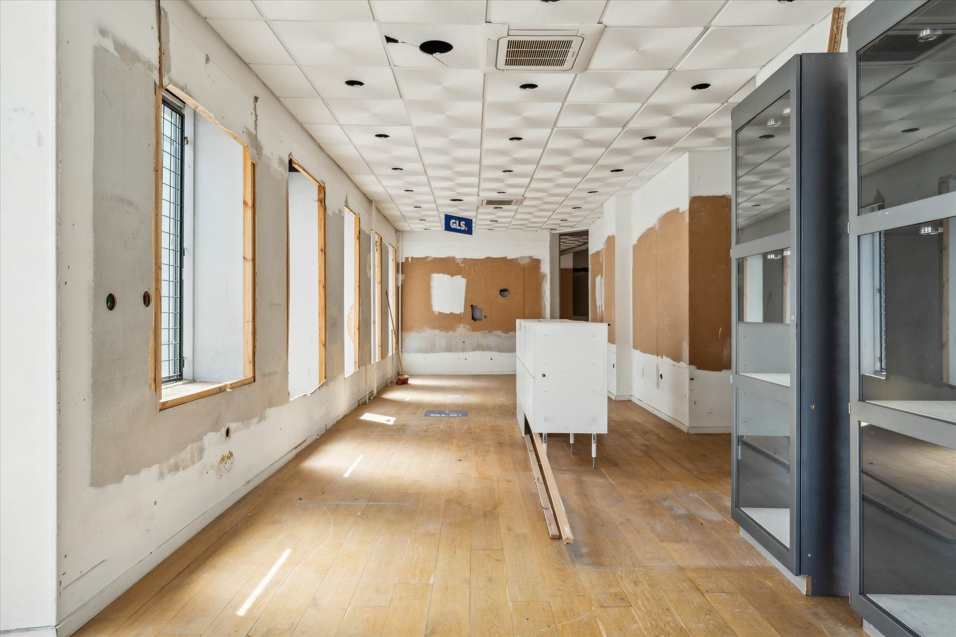 En tom og renoveret erhvervslokal med højt loft og vinduer, hvor væggene og gulvet er i reparation
