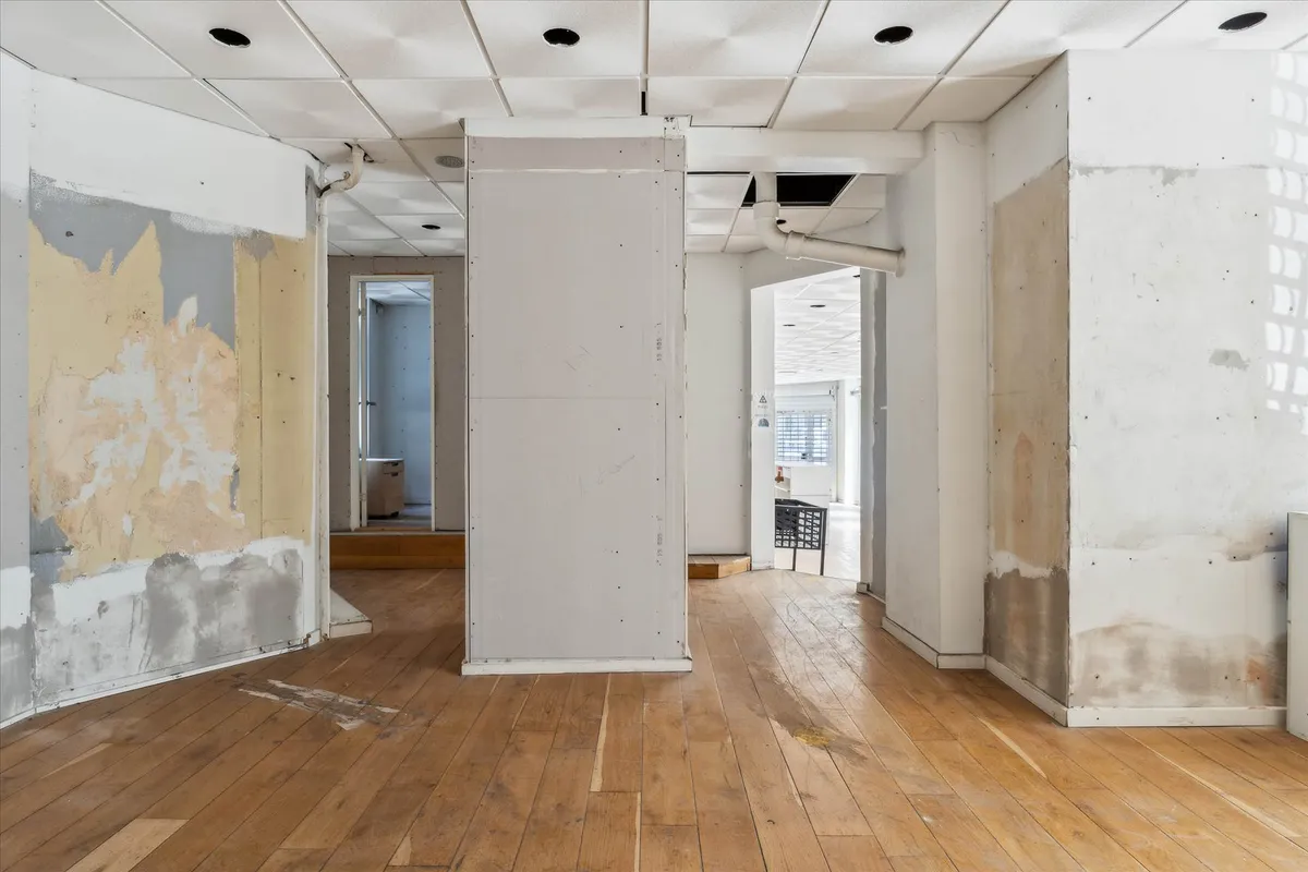 Lejlighed med renovering i gang, hjørneplacering, gulv, hvide vægge, gulv med revner, vinduer, og lyse gulvbelægning