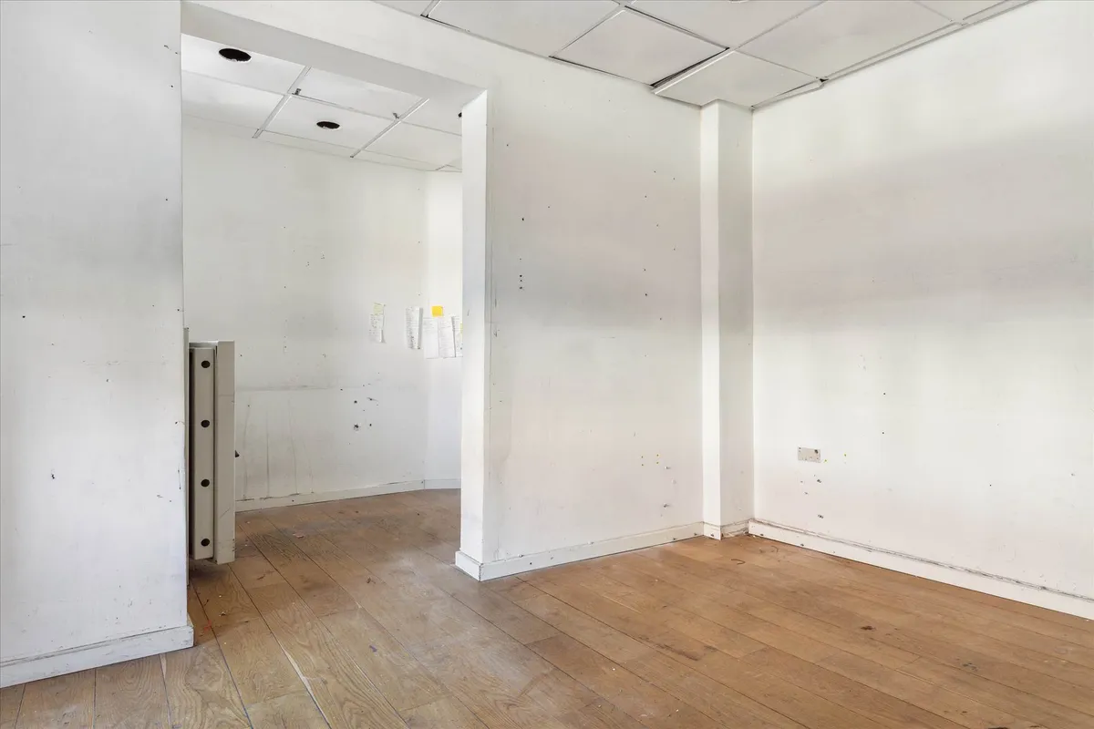 Kort og ligefremt rum med hvidt loft og gulv samt hvide vægge, der ser nye ud, og der er spor af papirstørklæder