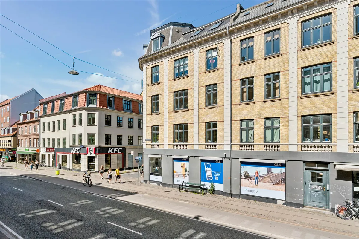 To KFC-restauranter i en bygning med glasruder og to etager og en GSL-butik med reklame på facaden