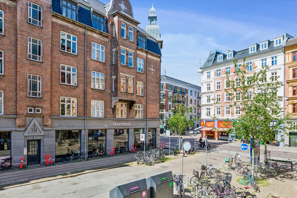 Elegant hjørnebygning med Desserthuset på hjørnet af Nørrebrogade og Heinesgade med flere vinduer og terrasse med planter og