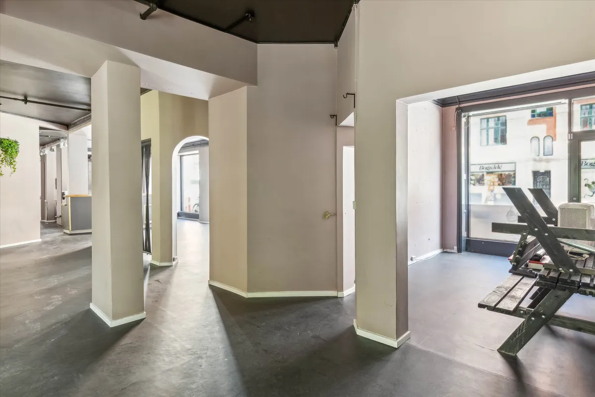 Store, moderne lokaler med lyse lofter og vinduer, krydsformede søjler, en stol og gulve med en grå tone