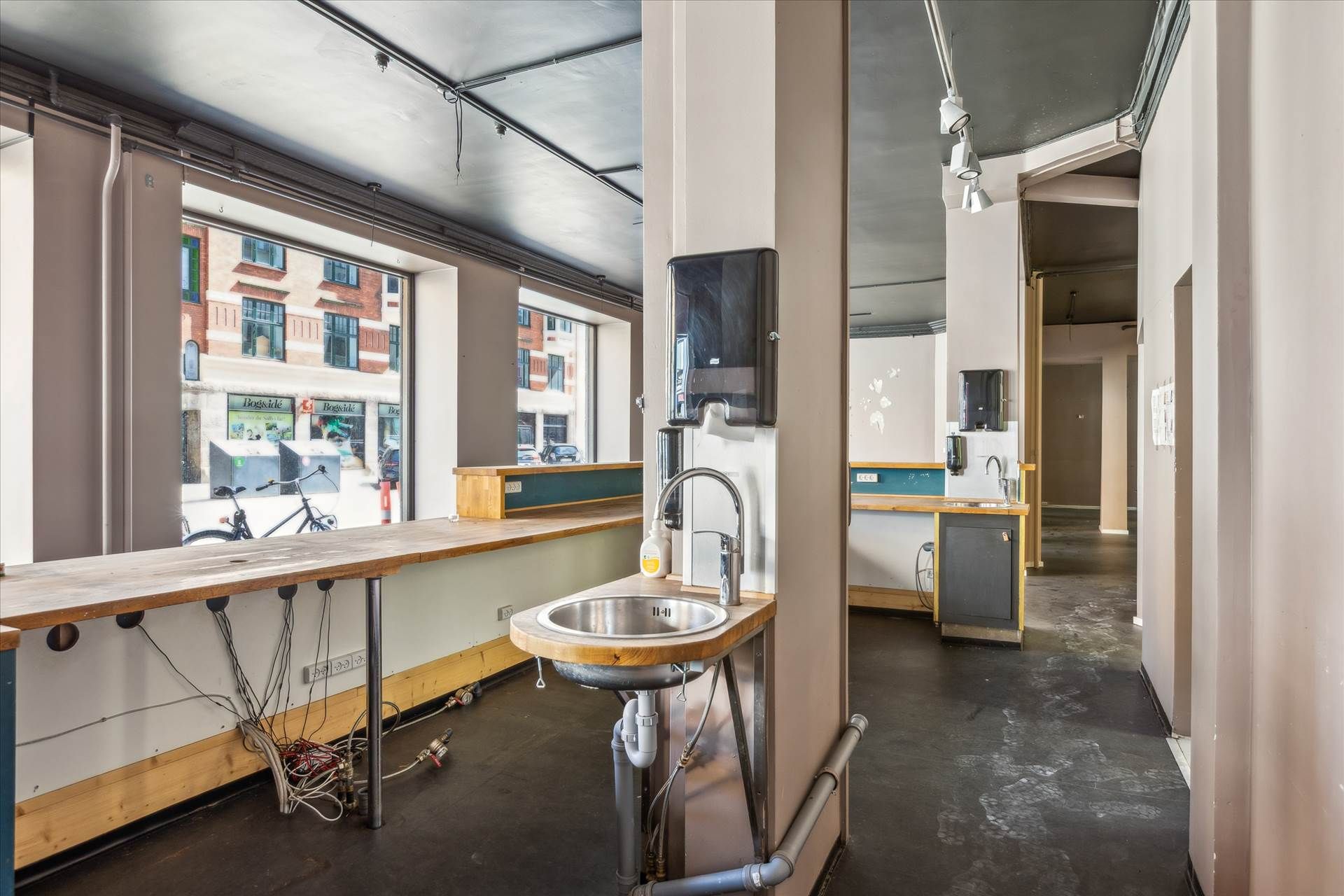 En tom værkstedsværelse med flere væskeudløb, to væskehåndled, og to lysekroner hængende fra loftet.