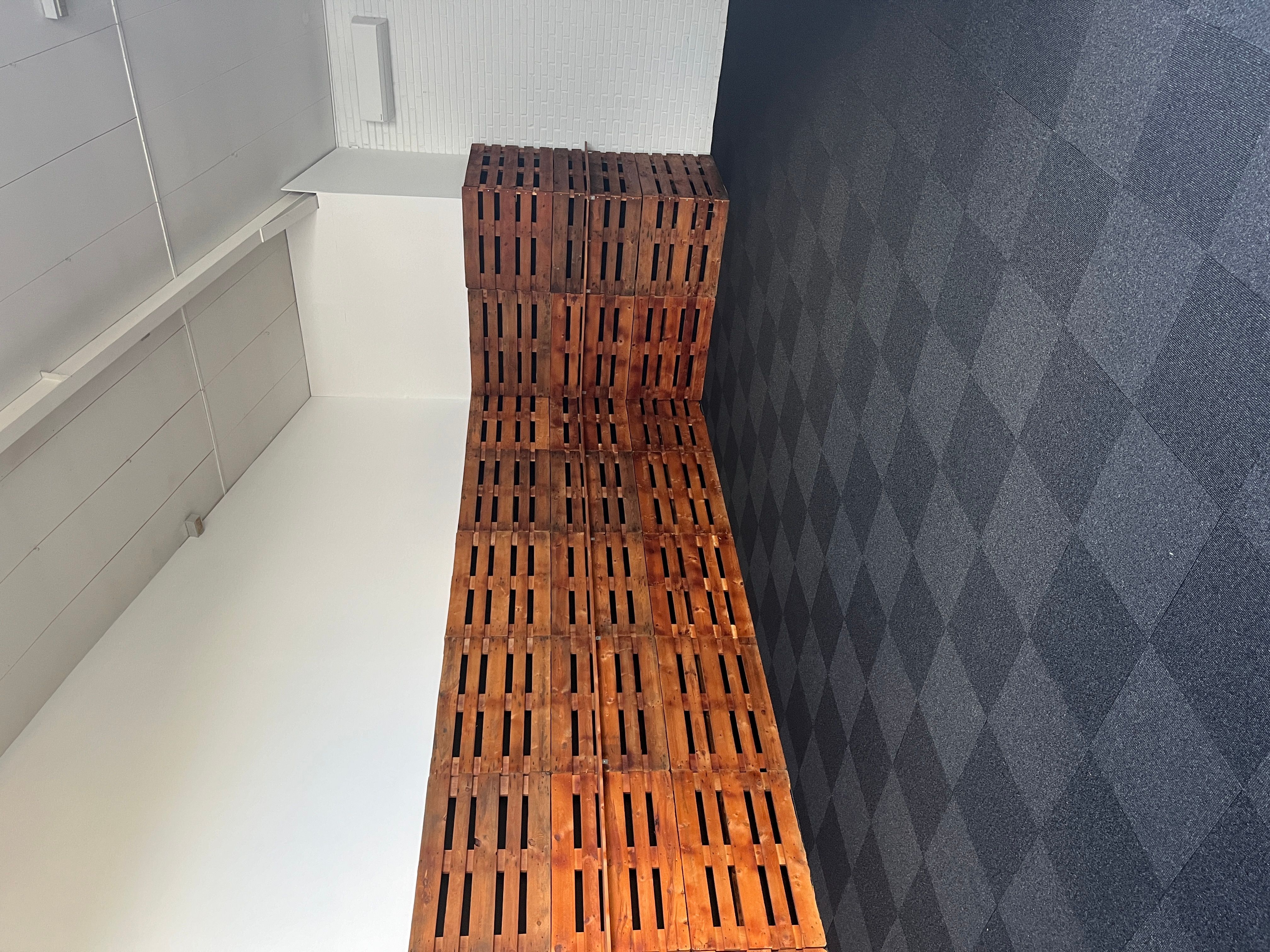 Træpæle er sammensat til en stol i et hjørne, hvor der er en hvid og en grågulv. Der er hvide vægge med hvide rammer og en