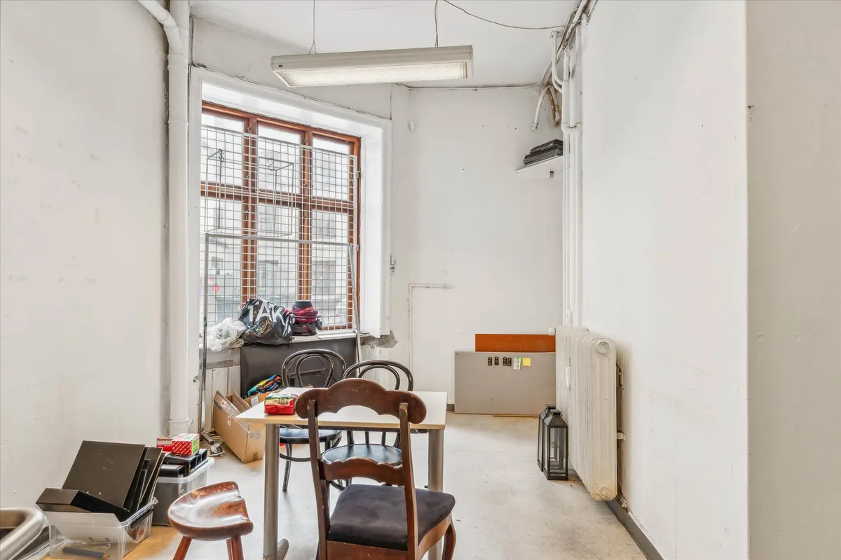 Butik med vinduer og møbler, en radiator og opbevaringsbokse, hvor flere ting er spredt rundt i rummet