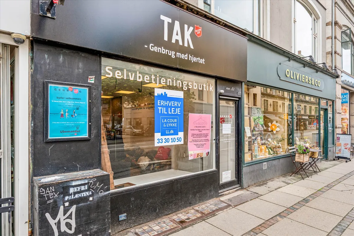 Tak genbrugsbutik på hjørnet af en gågade med mange forretninger og en lille terrasse med plantepotte