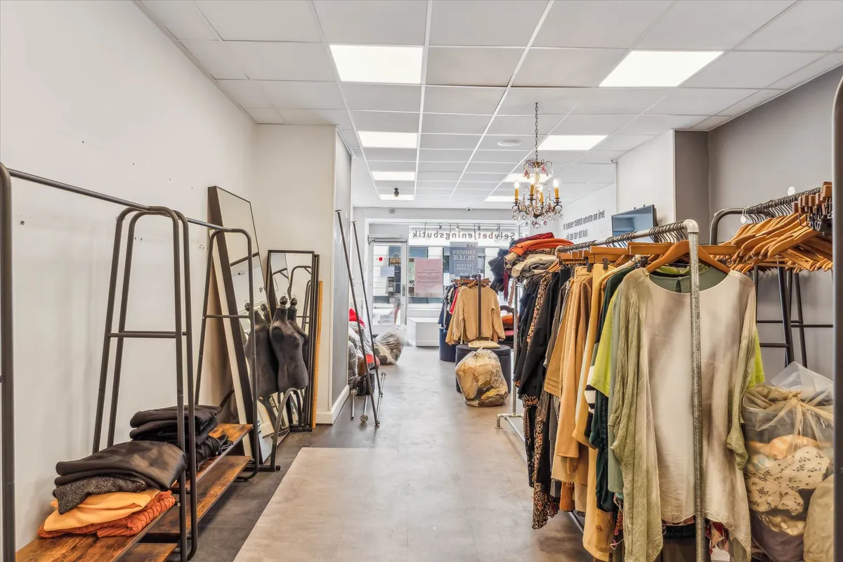 Værnedamsvejs genbrugsbutik med tøj og tøjlaus på hængere og stativer samt tøjsække og tøj på gulvet