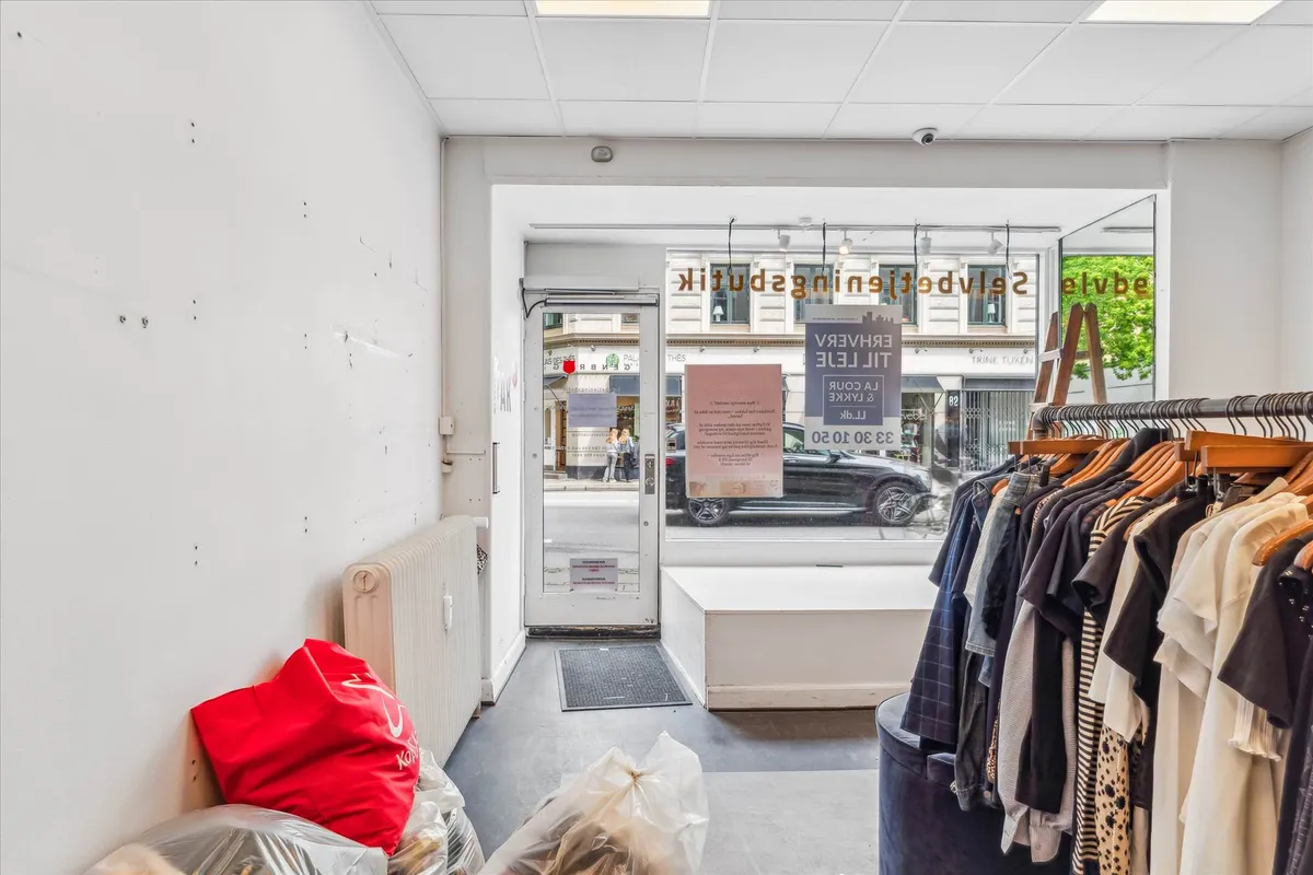 Butikslokaler med opbevaring og toilet, samt klædeholdere og tøj på træhylder og træhængere