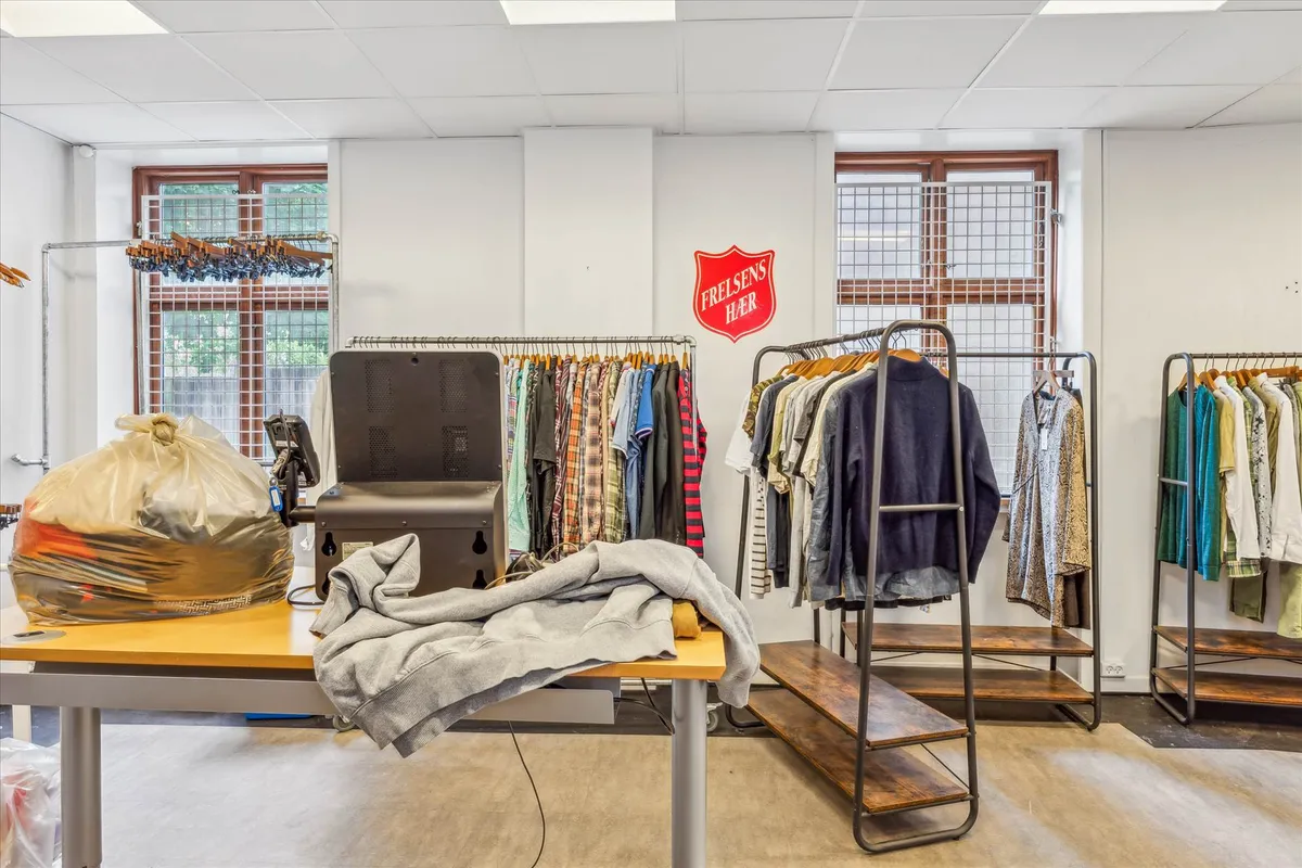 Genbrugsbutik med tøj og tøjvask, hvor der er plakat med Frelsens Hær, samt tøj på hylder og bord med tøjvask