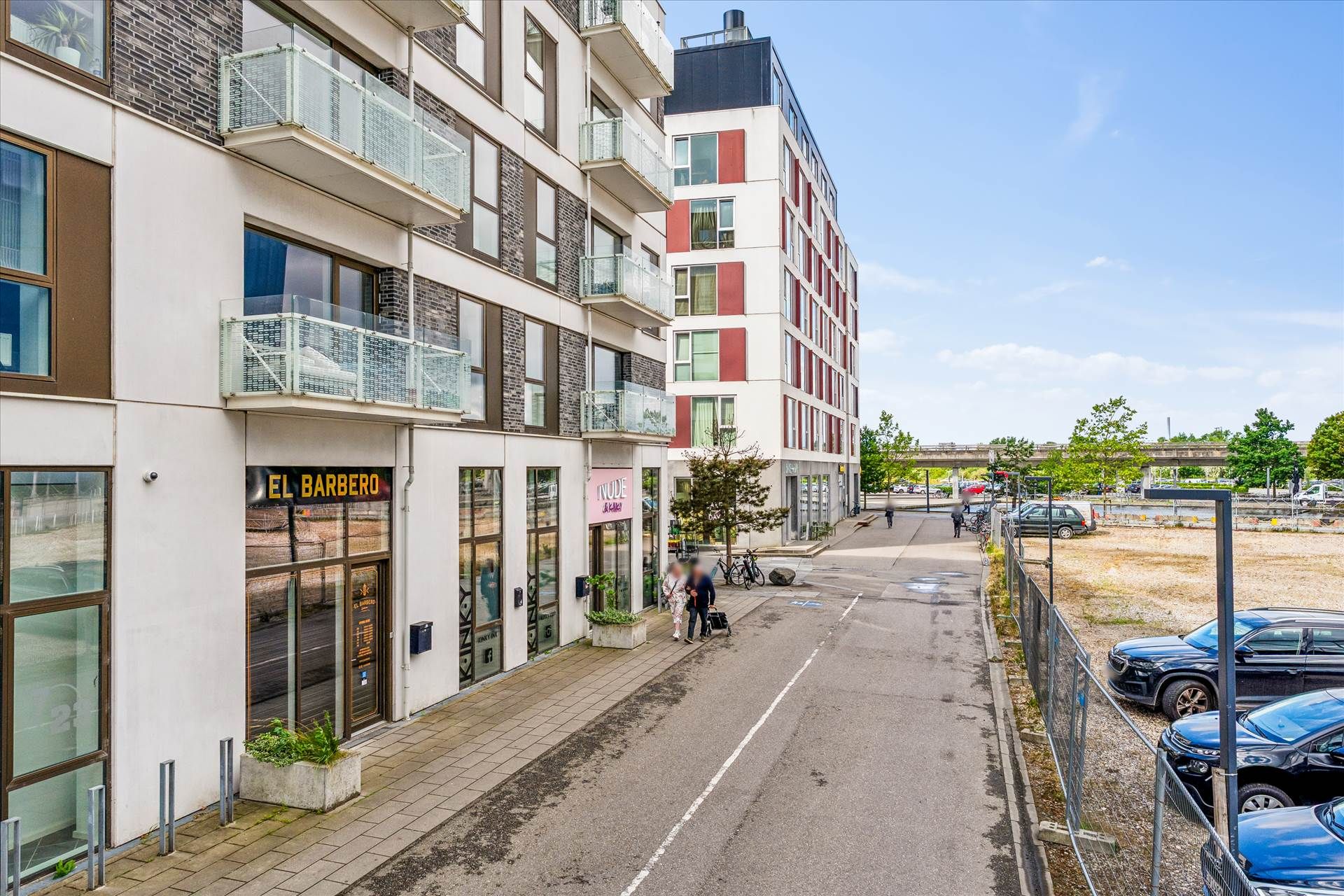 Et moderne kontorbyggeri med store glasvinduer og en stor parkeringsplads. Butikker og kontorer med store vinduer og