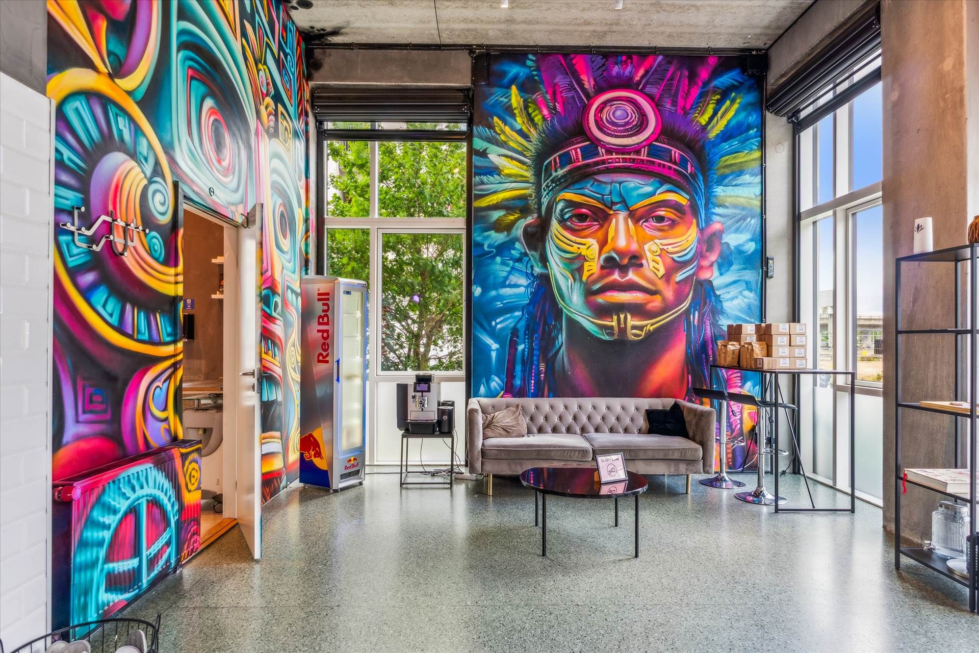 Inde i et moderne kontor med farverige vægmalerier og et stort maleri af en indianer med en farverig højhue