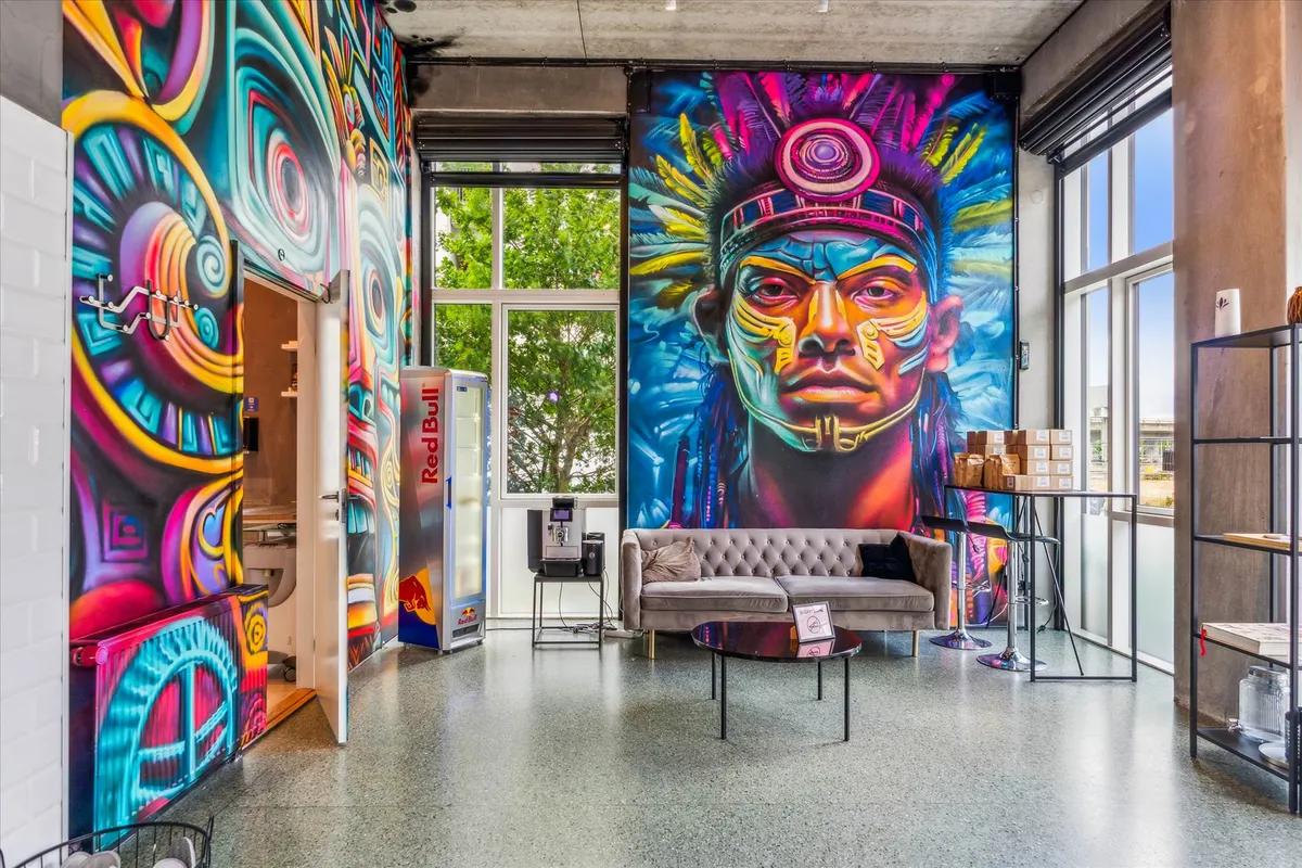 Inde i et moderne kontor med farverige vægmalerier og et stort maleri af en indianer med en farverig højhue