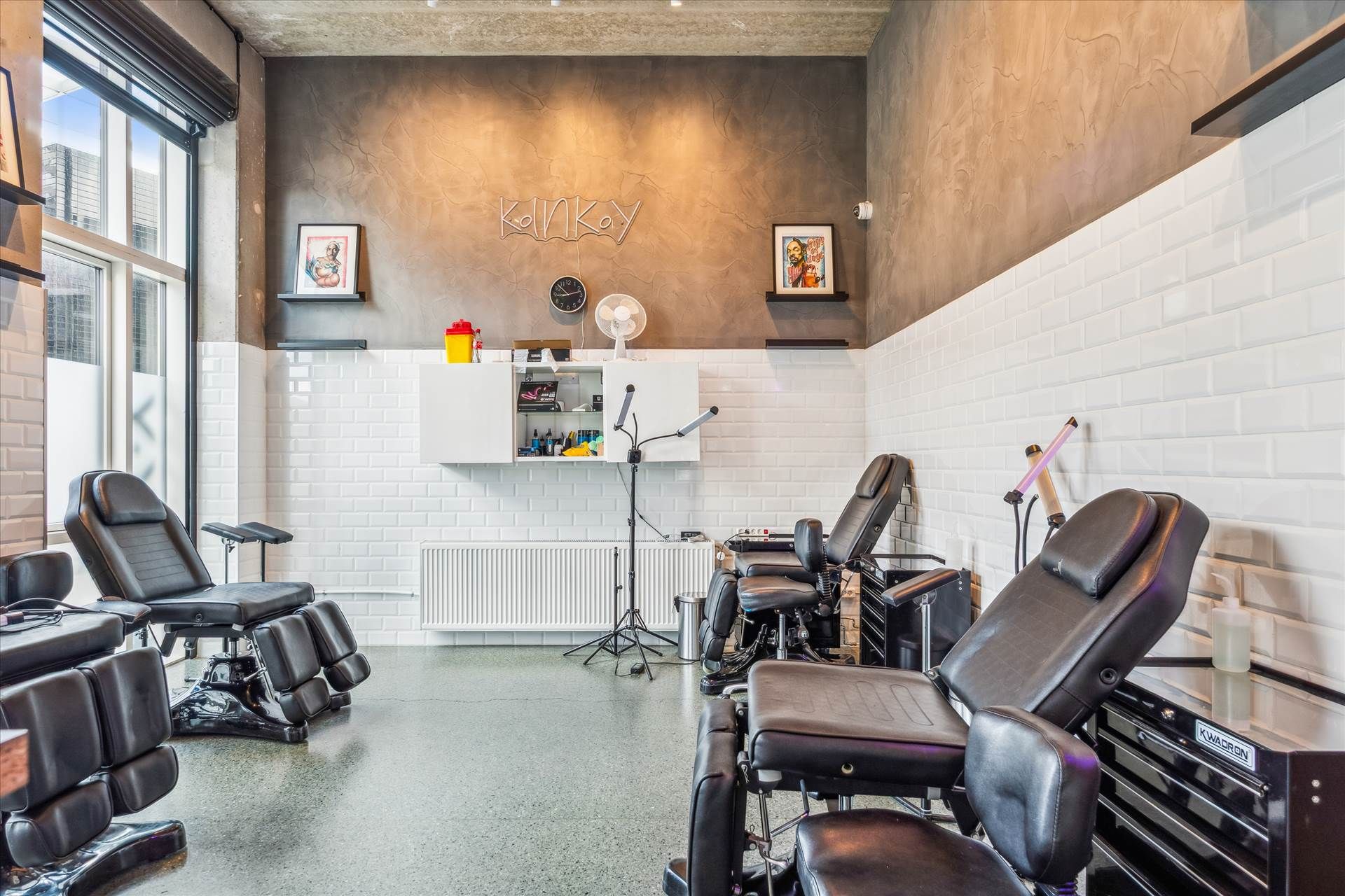 Tatoveringssalon med moderne møbler og udstyret til tatovering. Salonen har lyse farver og flere tatoveringsstole.