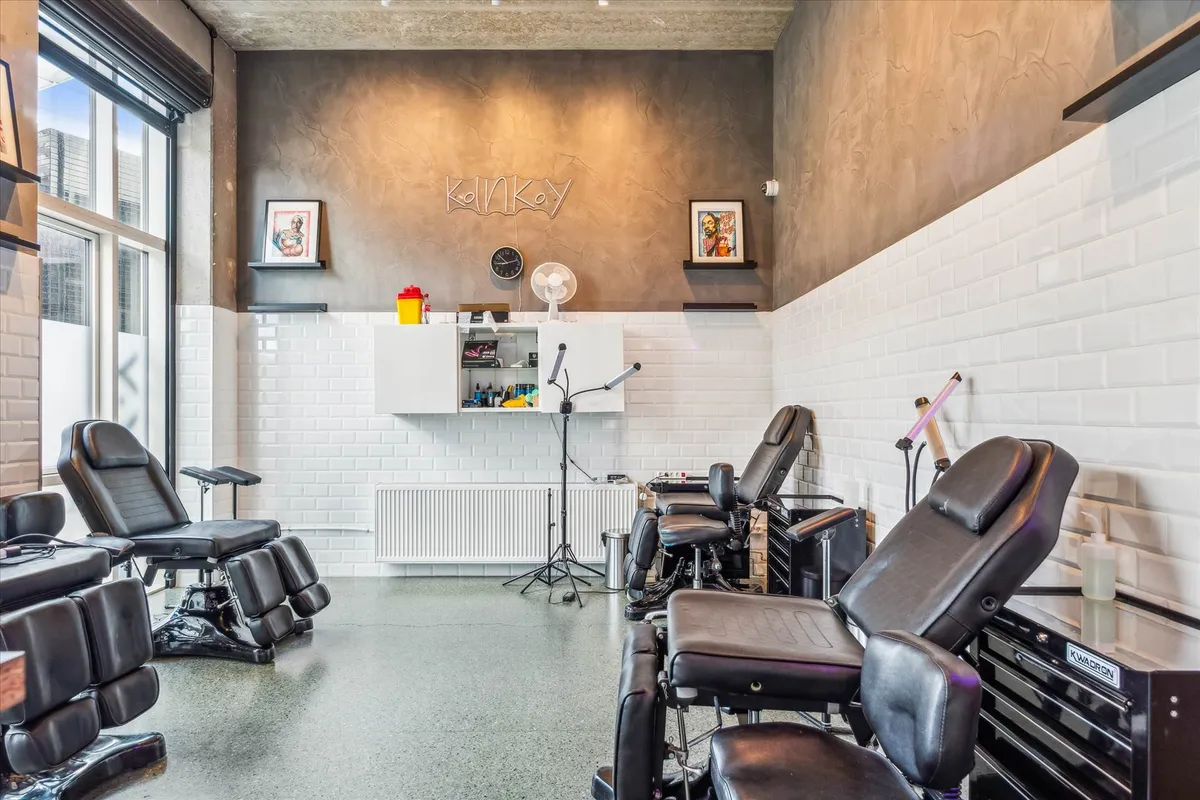 Tatoveringssalon med moderne møbler og udstyret til tatovering. Salonen har lyse farver og flere tatoveringsstole.