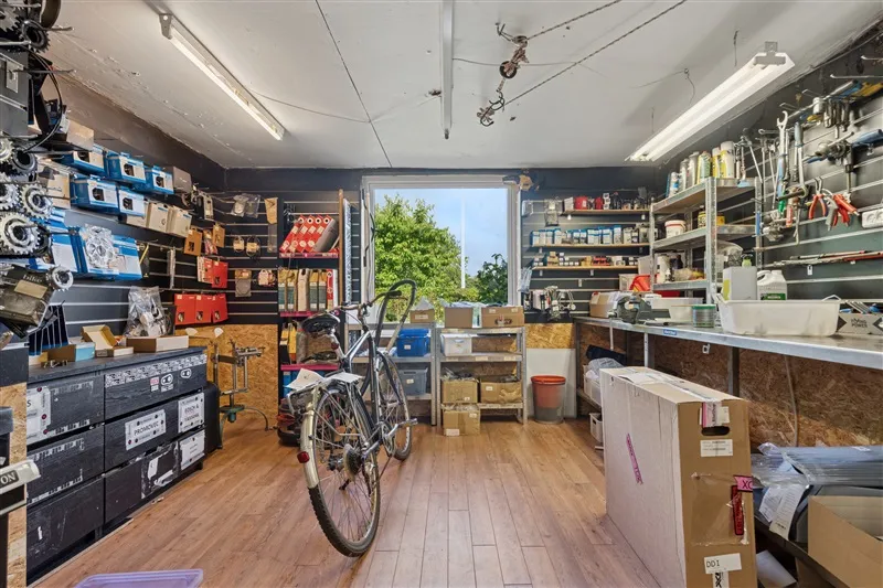 Garage med cykel, hylder og værktøj samt to lysarmaturer på loftet