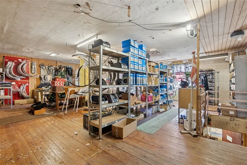 Lager med mange hylder, kasser, bokse og redskaber og røde vægge med skilte og udstyr