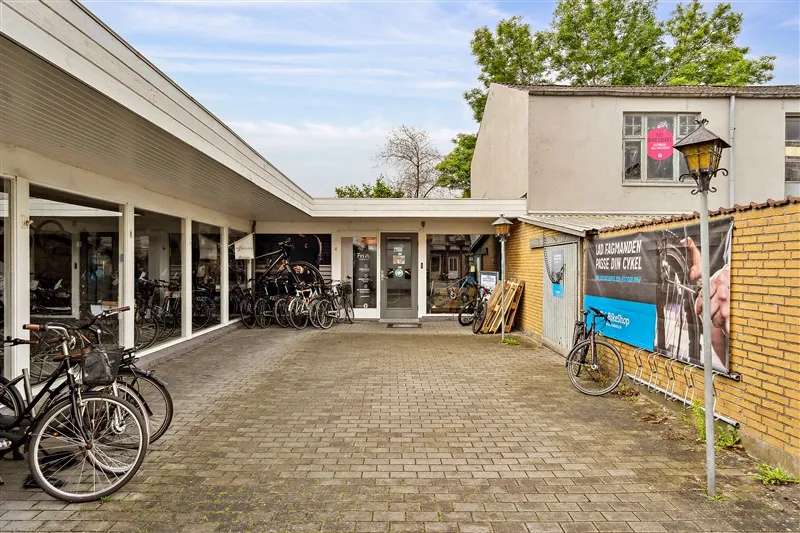 En cykelforretning med flere cykler parkeret udenfor og en skilt med teksten "Lad Fagmand"