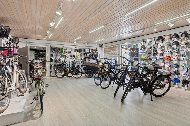 Cykelforretning med udstilling af forskellige cykler og hjelm samt lysekroner og vinduer i loftet