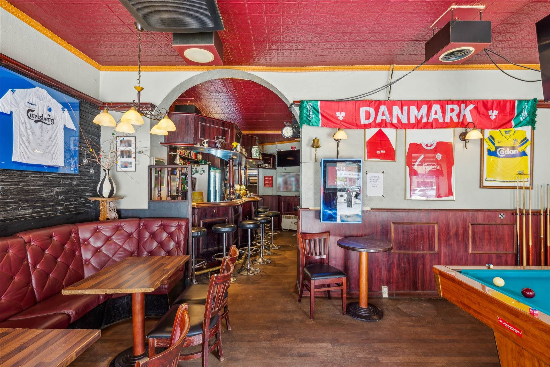 Lyssalgssted med røde sofaer og bord og stol i København, samt poolbord og Carlsberg-reklame