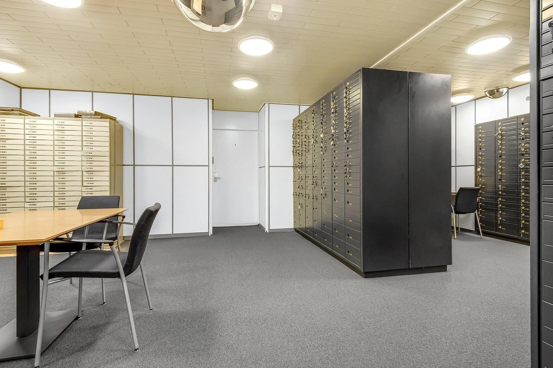 Værelse med en stor sort skab og en gul bord med to møbler samt et hvidt væg med dør