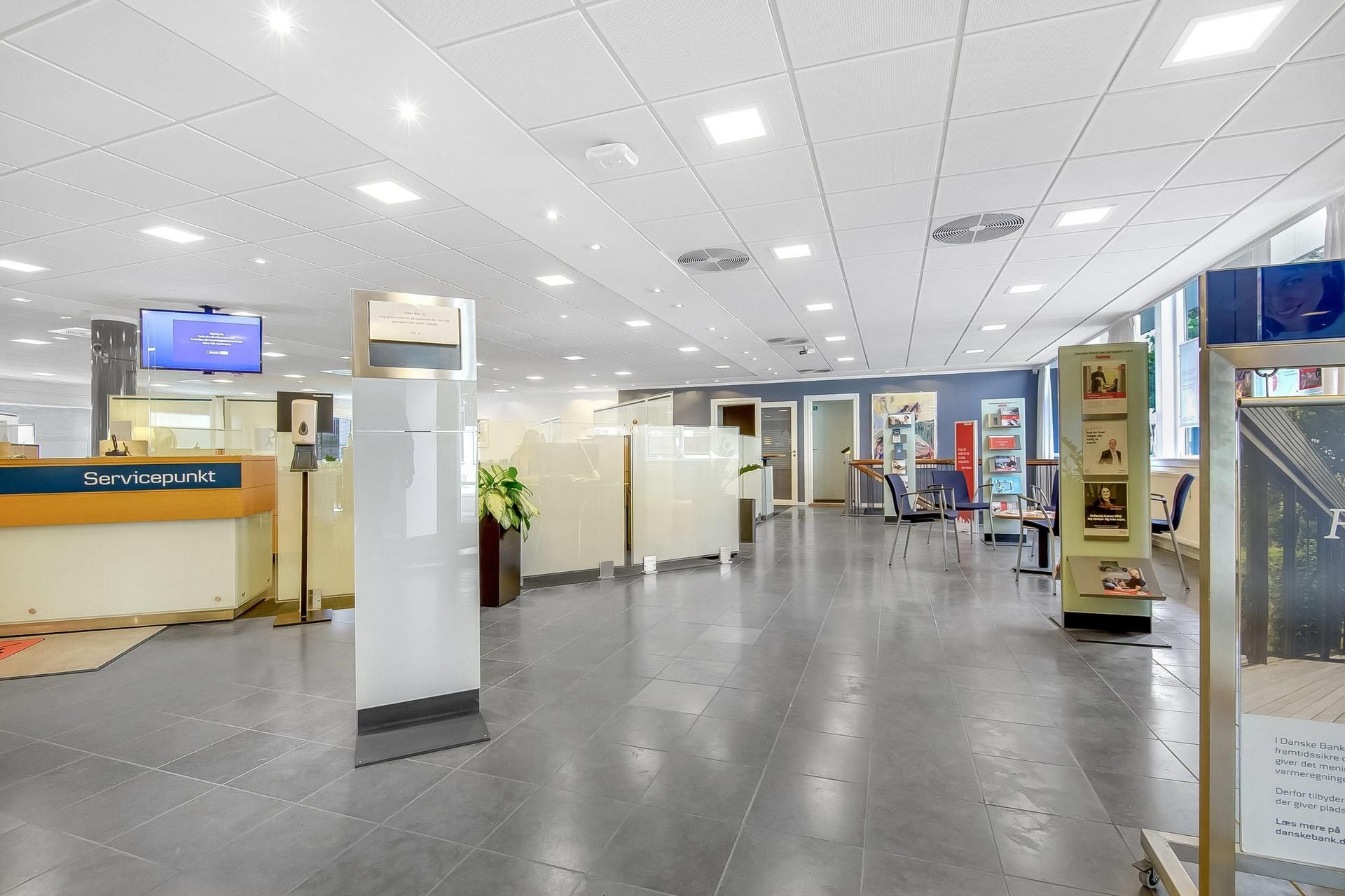 Flisegulv, trægulv og gulvbelægning. Servicepunkt og møbler. Billede af kvinde og mand. Kasseapparater og reklamemateriale.