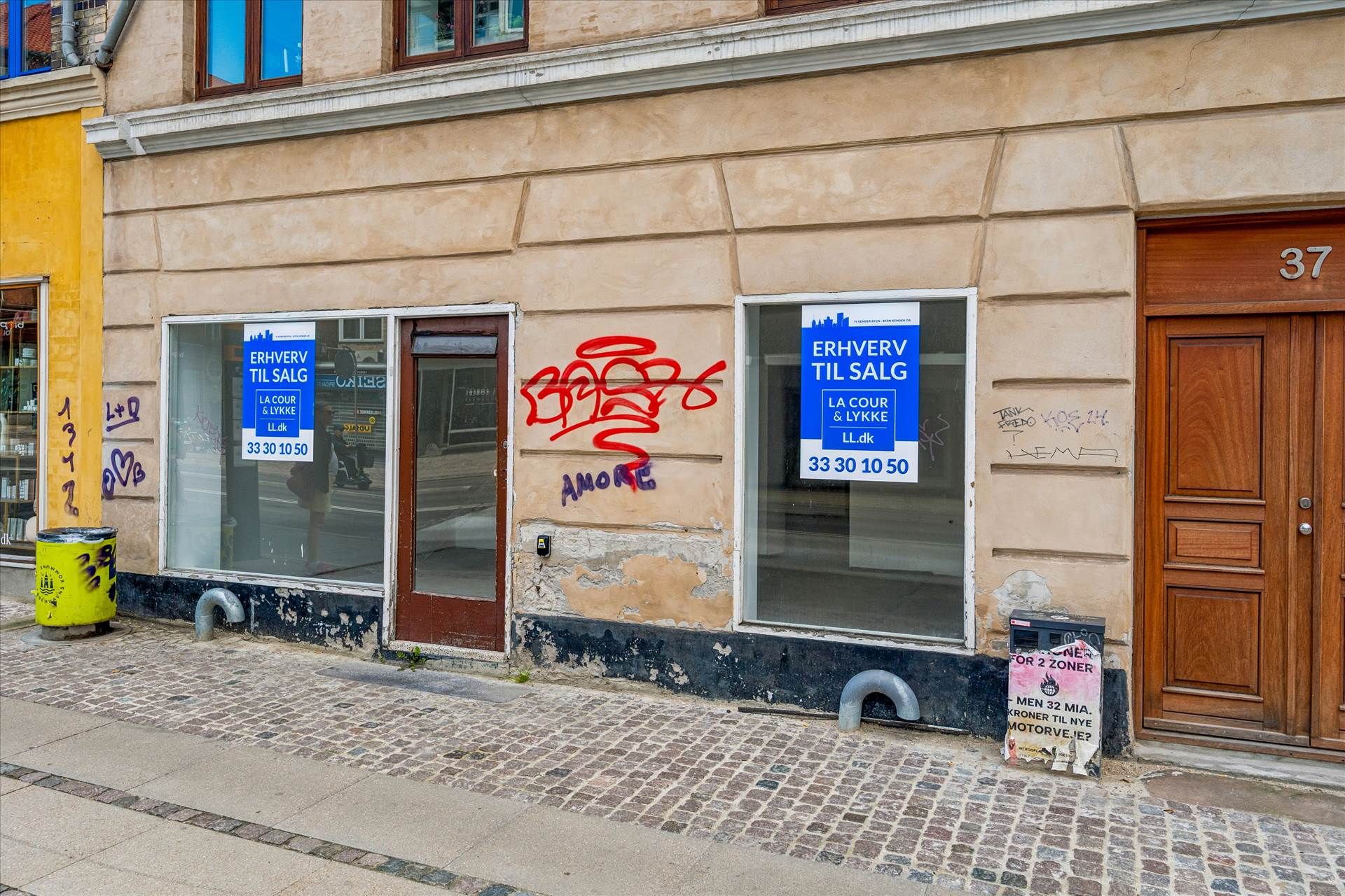 To erhvervslejligheder er til salg med skilte på Valby Langgade, med graffiti og parkeringsmappe i nærheden