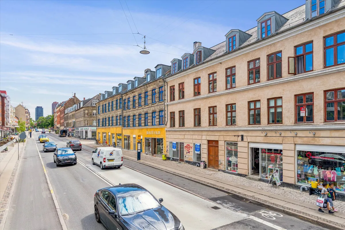 På Valby Langgade kører biler langs fortovet med forretninger og butikker, herunder Tøjeksperten Store Robert. Her er også