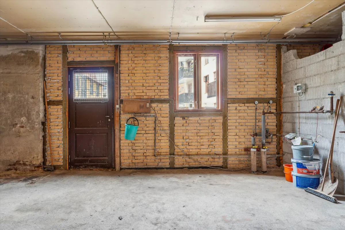 En tom garage med rå gulv og vægge, stakkels møbler og værktøj, rødt tøndebælt, lysekroner og vinduer