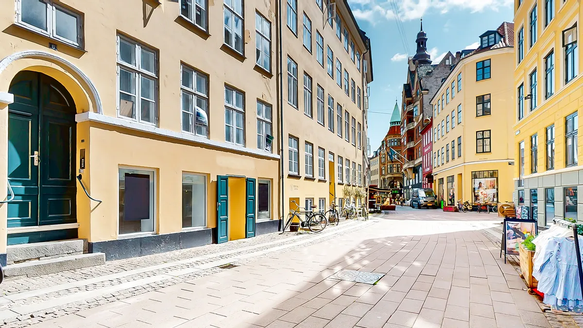 Butik med grønne døre og gul indgangsdør placeret på en travl og fuld af liv gade i København