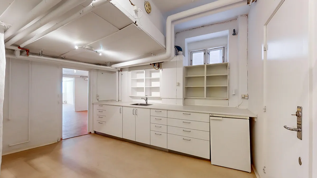 Et moderne og rent køkken med hvide vægge, en hvid indbygget komfur, lyseskabe og en stor række køkkenskabe med masser af