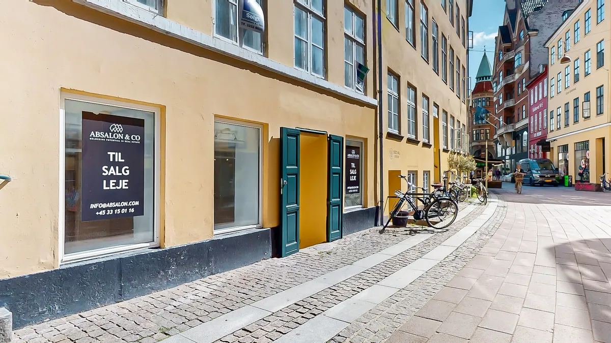 Et lejlighedsvindue med teksten Til Salg Leje på dansk og info@absalon.com på reklameskilten
