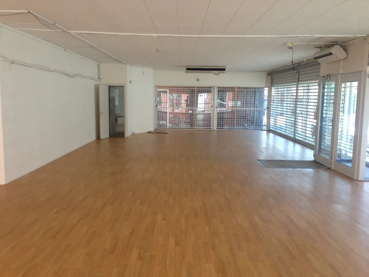 En stor, tom lejlighed med højt til loftet, vinduer og en glasdør til gaden og lufthavnsluft.