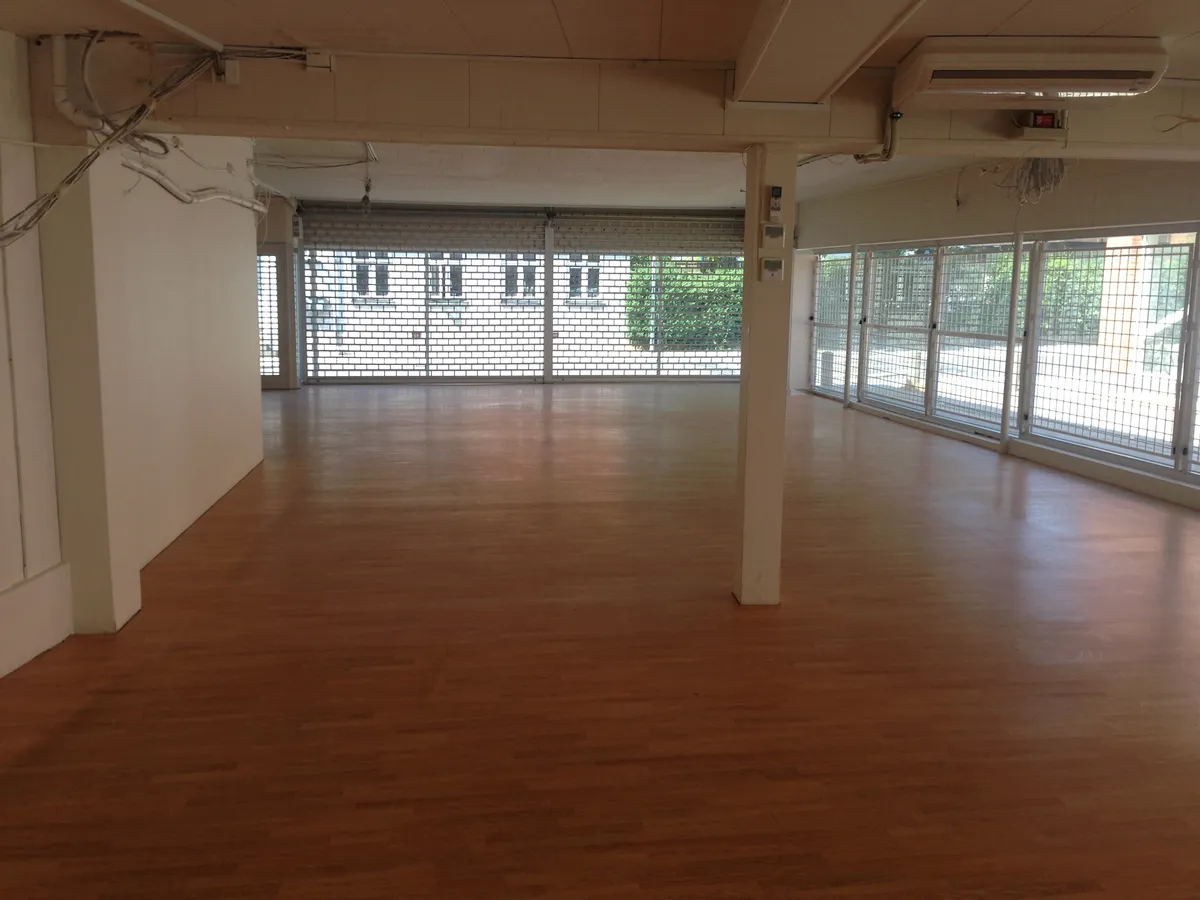 En stor tom lejlighed med store vinduer og trægulv og højt loft, der er udstyret med klimaanlæg og elektriske ledninger