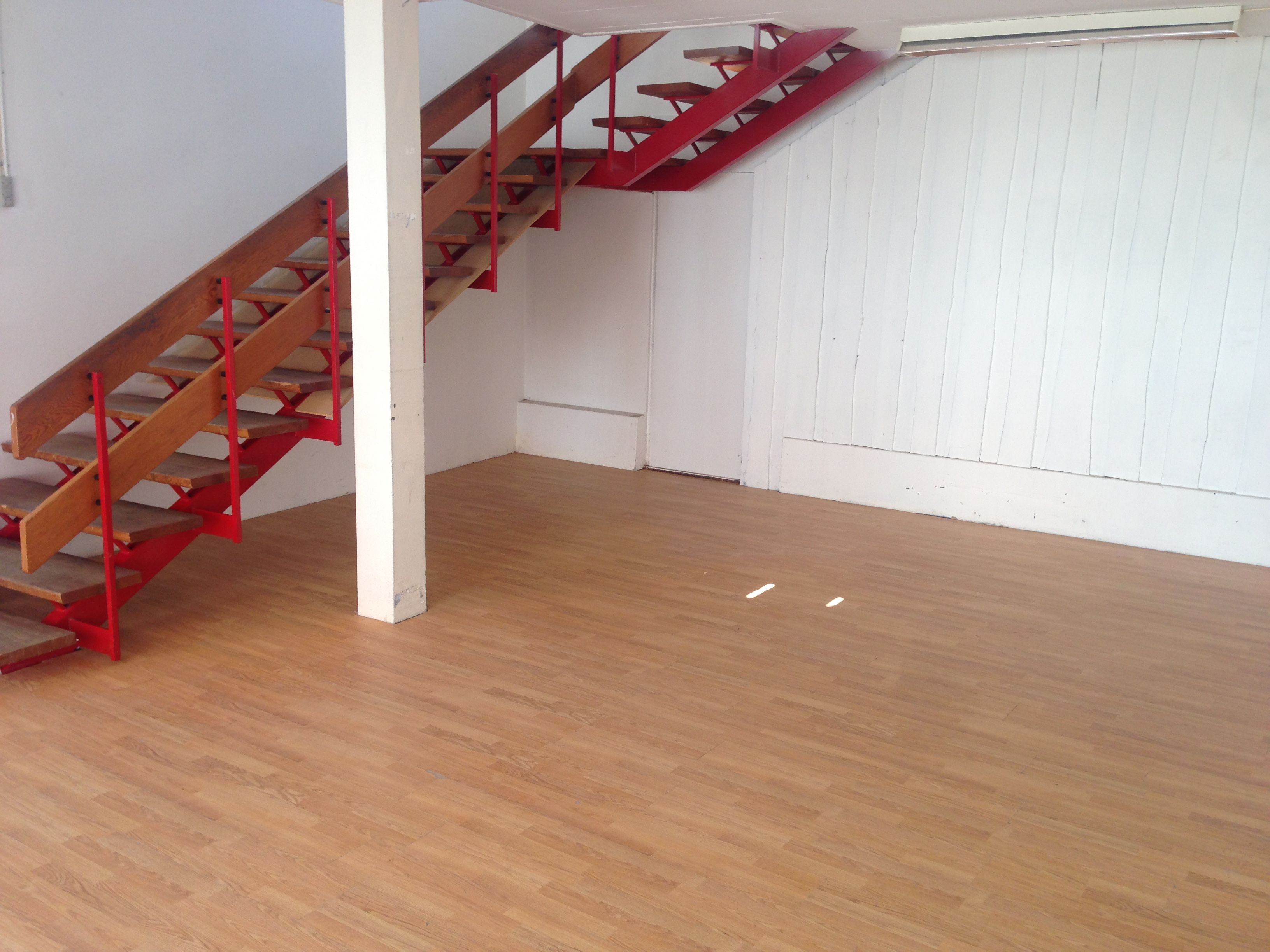 Store lejlighed med loft og højloft, to forskelige typer gulvbelægning og røde trapper.