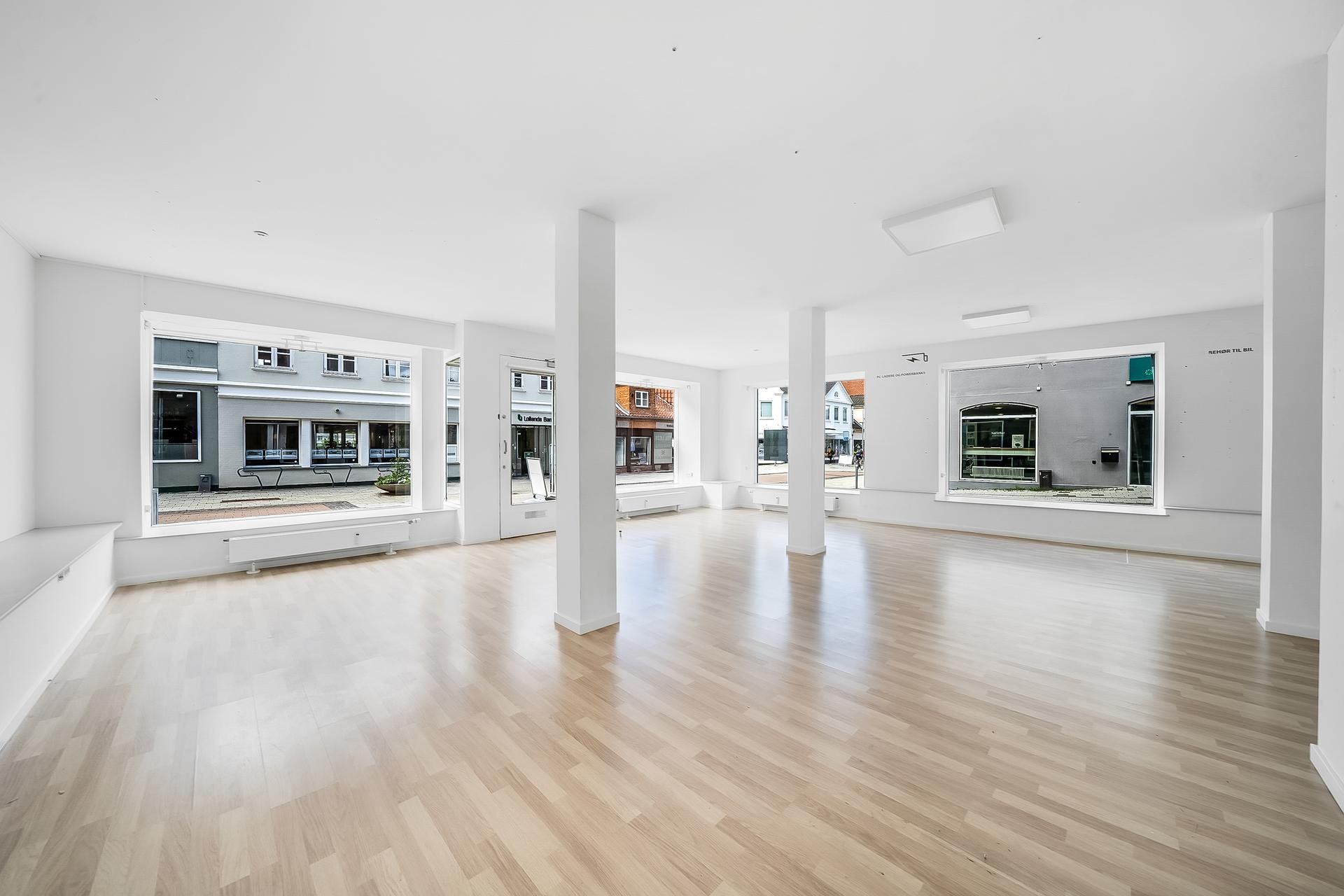 Butikslokaler med lyse lofter og gulv samt store vinduer mod gaden