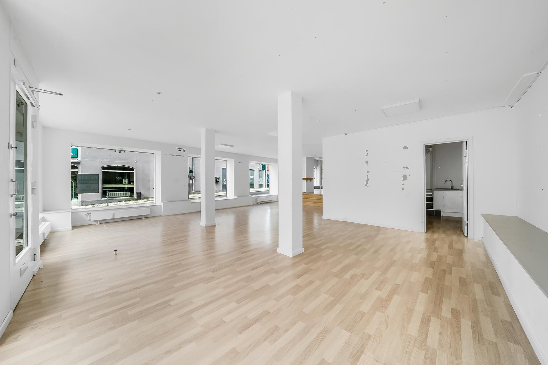 En tom, lys og rummelig værkstedslokal med lyse trægulve og hvide vægge og døre