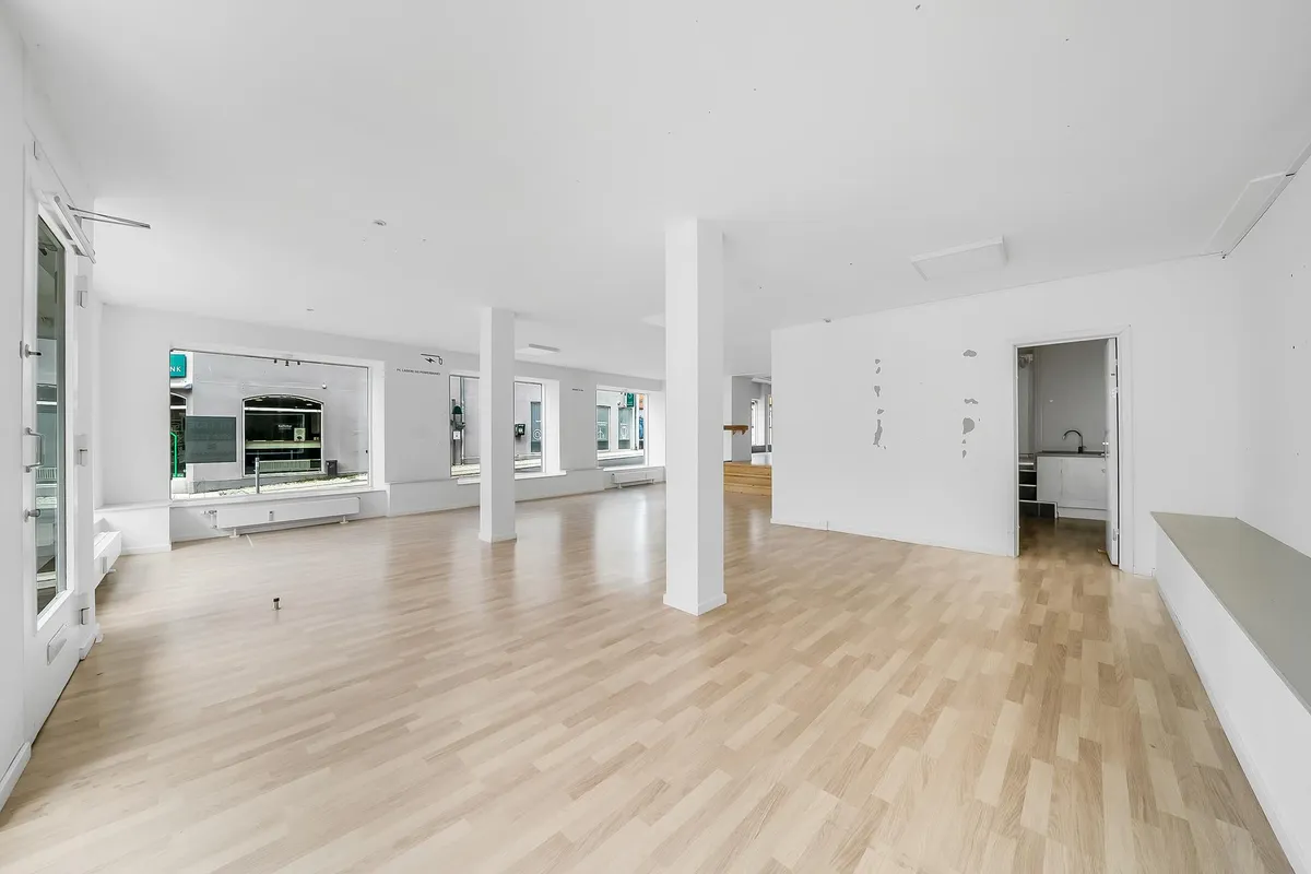 En tom, lys og rummelig værkstedslokal med lyse trægulve og hvide vægge og døre
