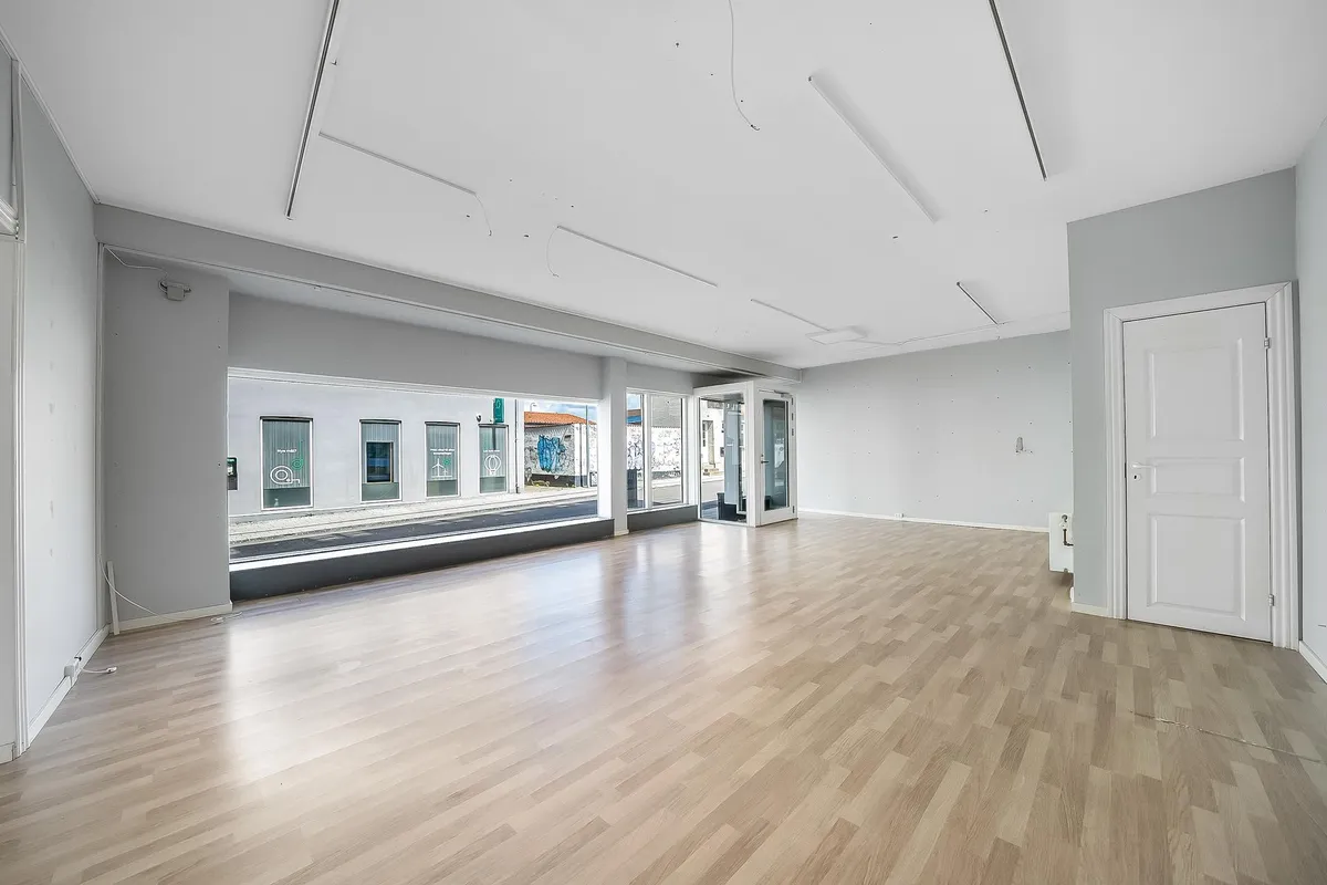 Store lokaler med højloft og lysegult gulv. Store vinduer med udsigt til hovedgaden. En dør er åben og leder ind i et tomt