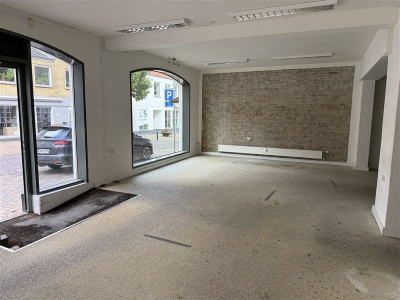 Et moderne kontor med to store glasruder og parkeringsskilt på gaden udenfor