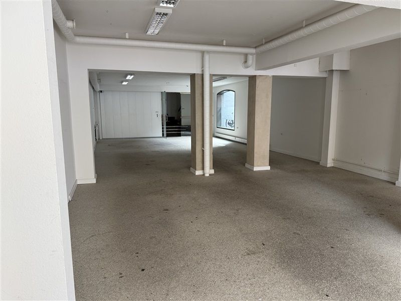 En tom lejlighed med hvide vægge og gulv, højt til loftet og to store vinduer