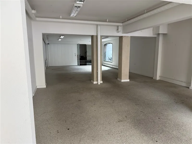 En tom lejlighed med hvide vægge og gulv, højt til loftet og to store vinduer