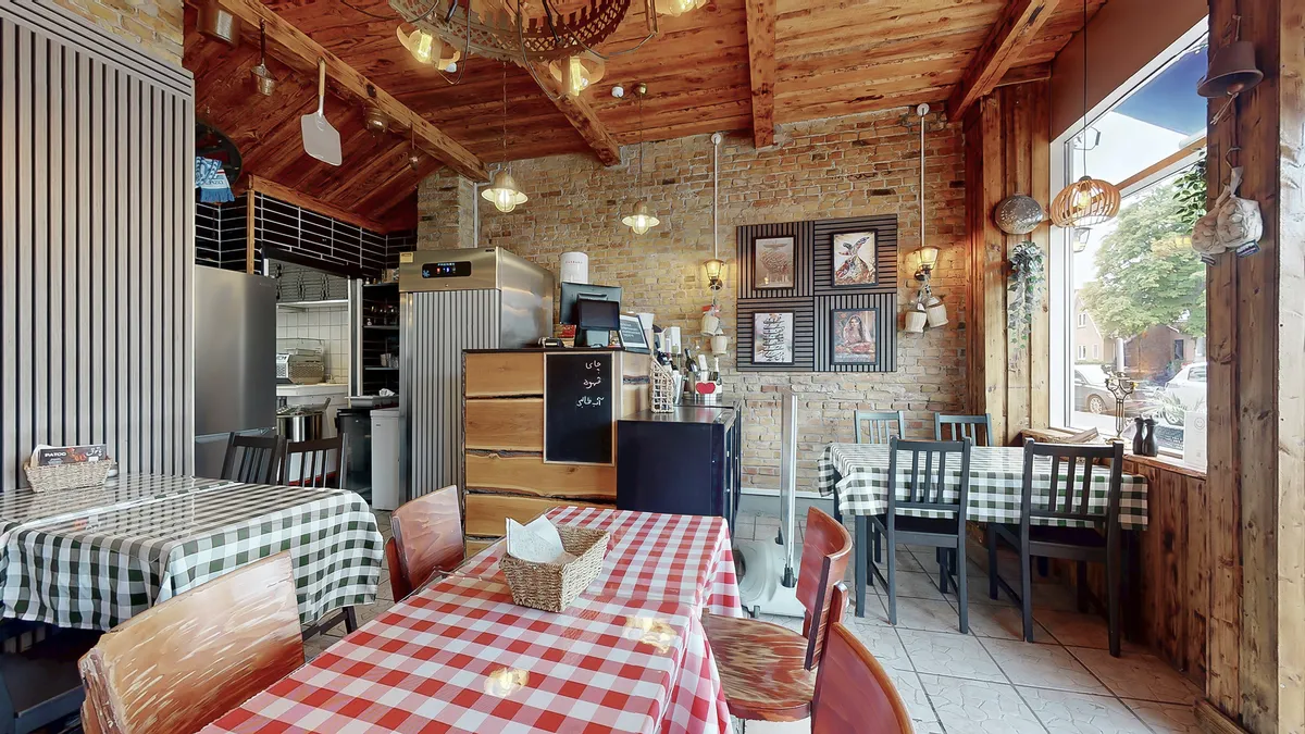 Interiør med bord og stole i et amerikansk steakhouse med servietter i kurve og menutavle i loftet