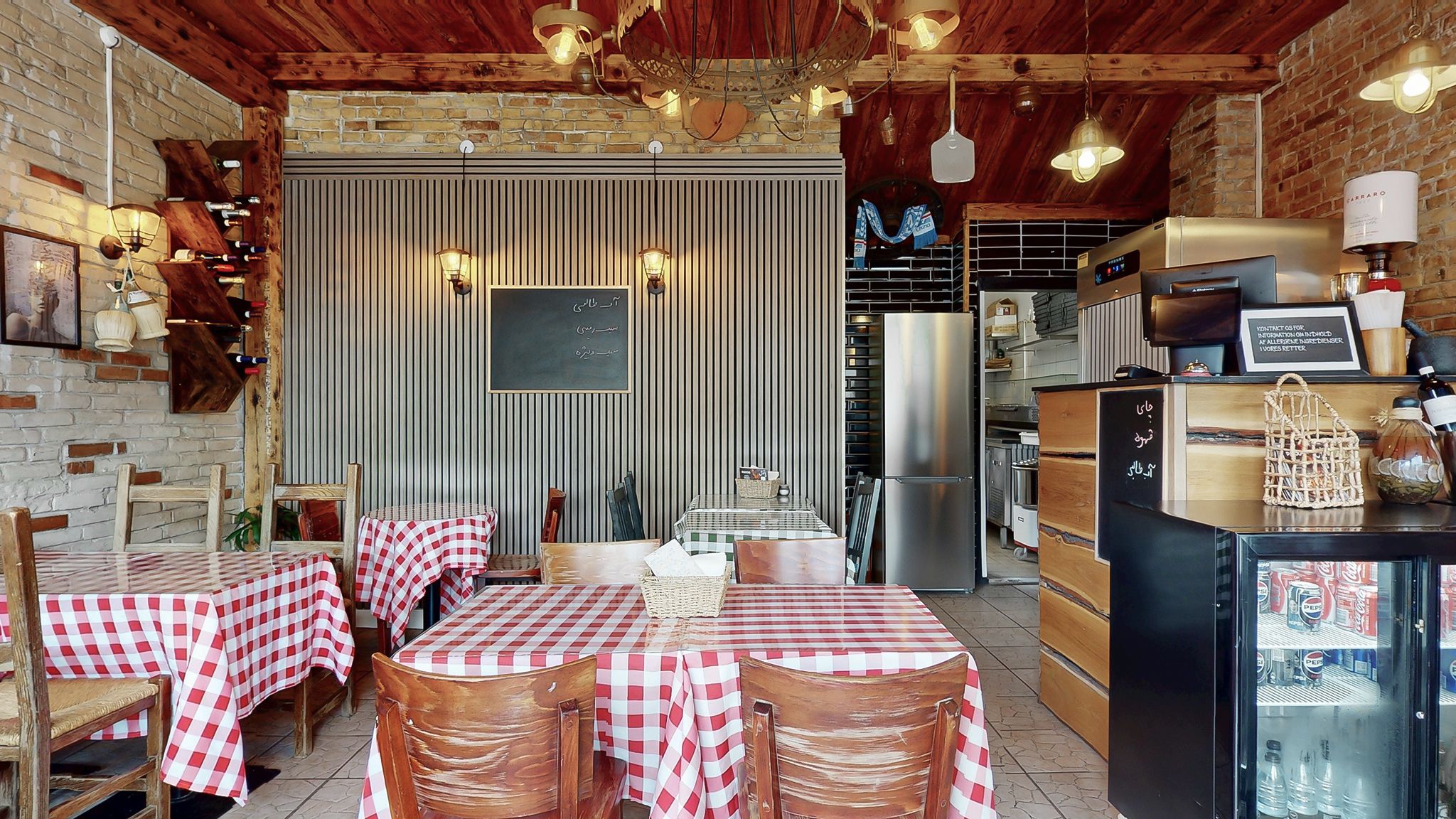 Et indretningsrum med to røde og hvide bordklæder. Der er to køleskabe og en indbygget ovn i rummet. Der er en sort køleskab