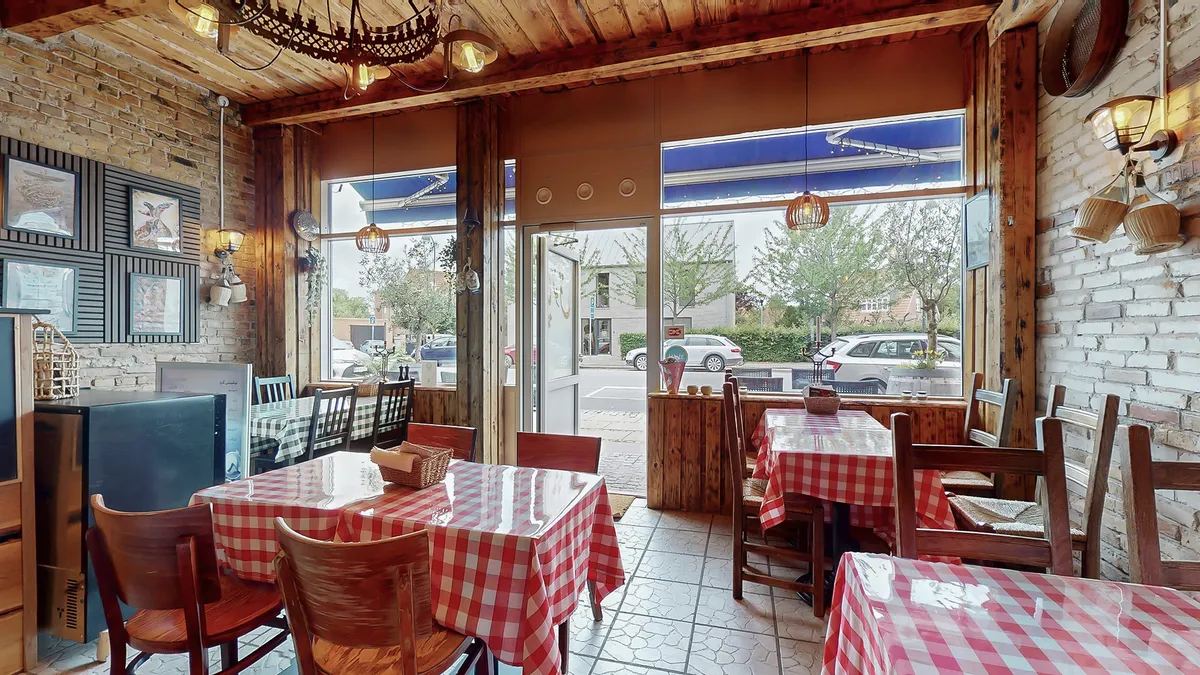 Interiør i en italiensk restaurant med en stor glasdør og vinflasker hængende på væggen