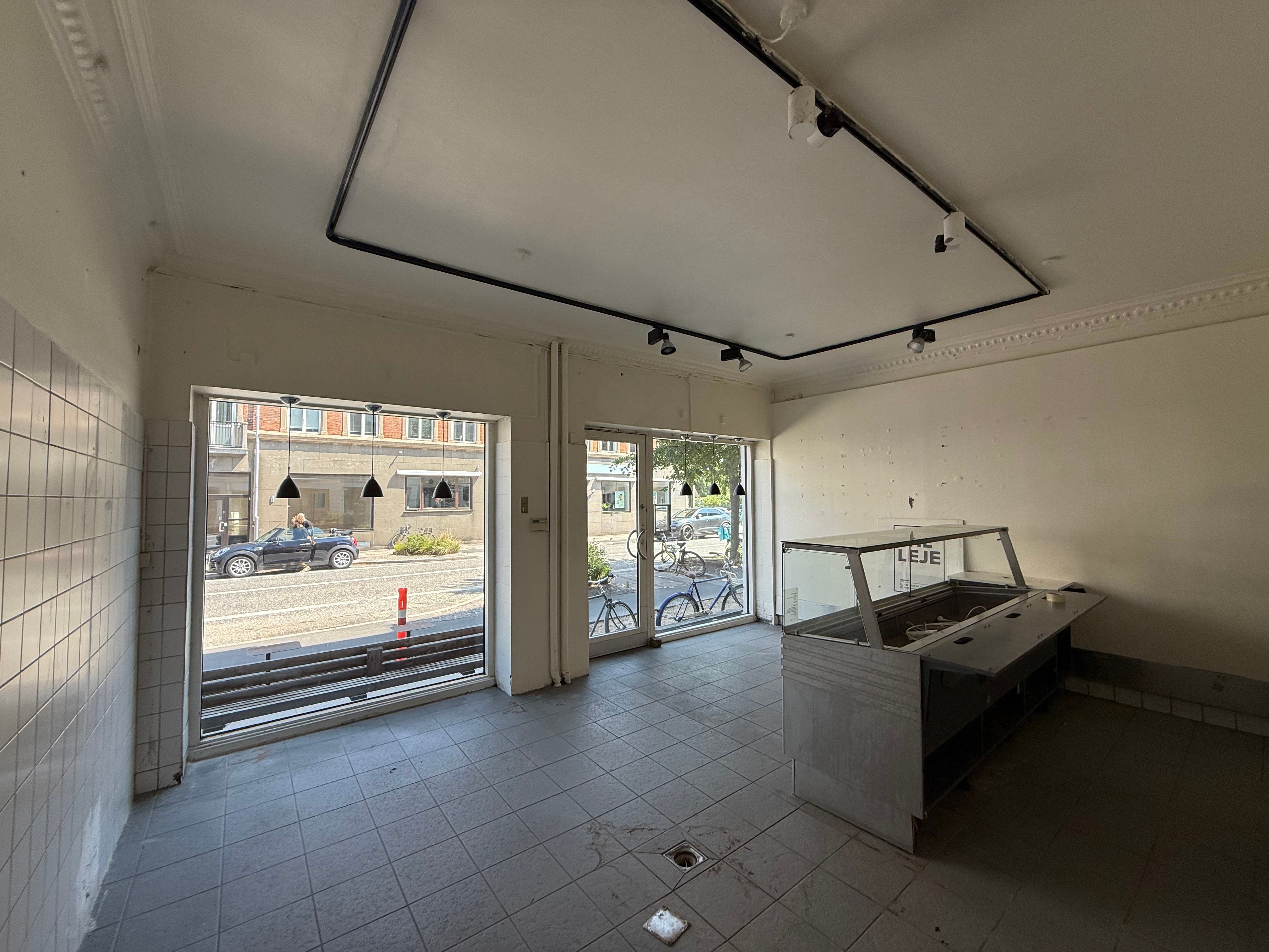 Take-away i Hellerup med store vinduer, åben og rummelig indretning og udsigt til Strandvejen og parkeret bil og cykler