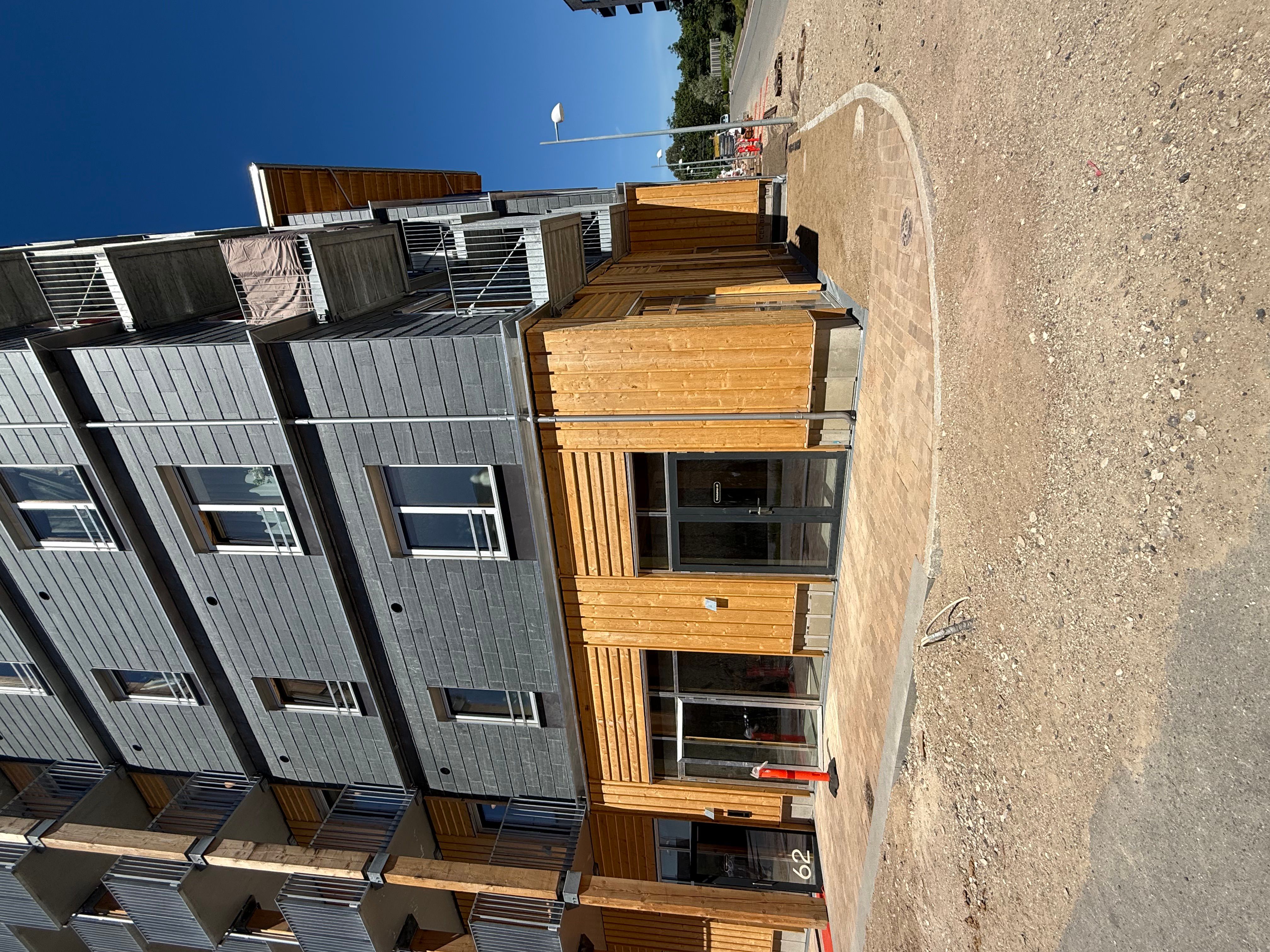 Bygning i tre etager med moderne design og træindslag, mørke ruder og udvendigt træværk