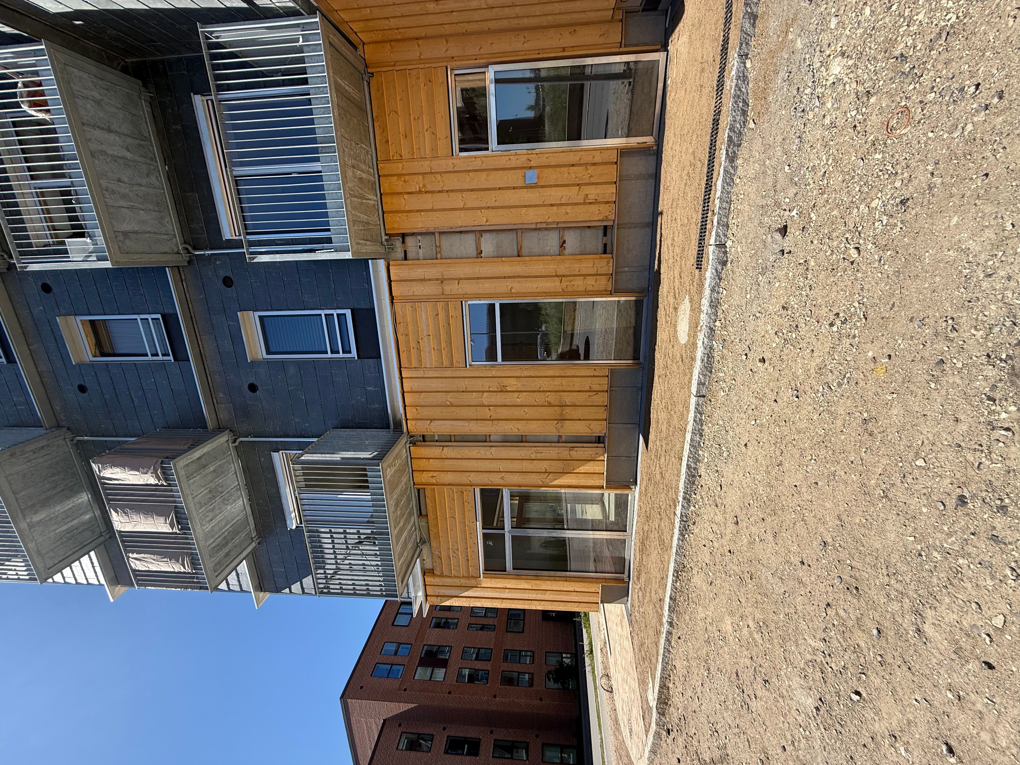 Moderne bygning med træbeklædning og flere etager med vinduer og balkoner