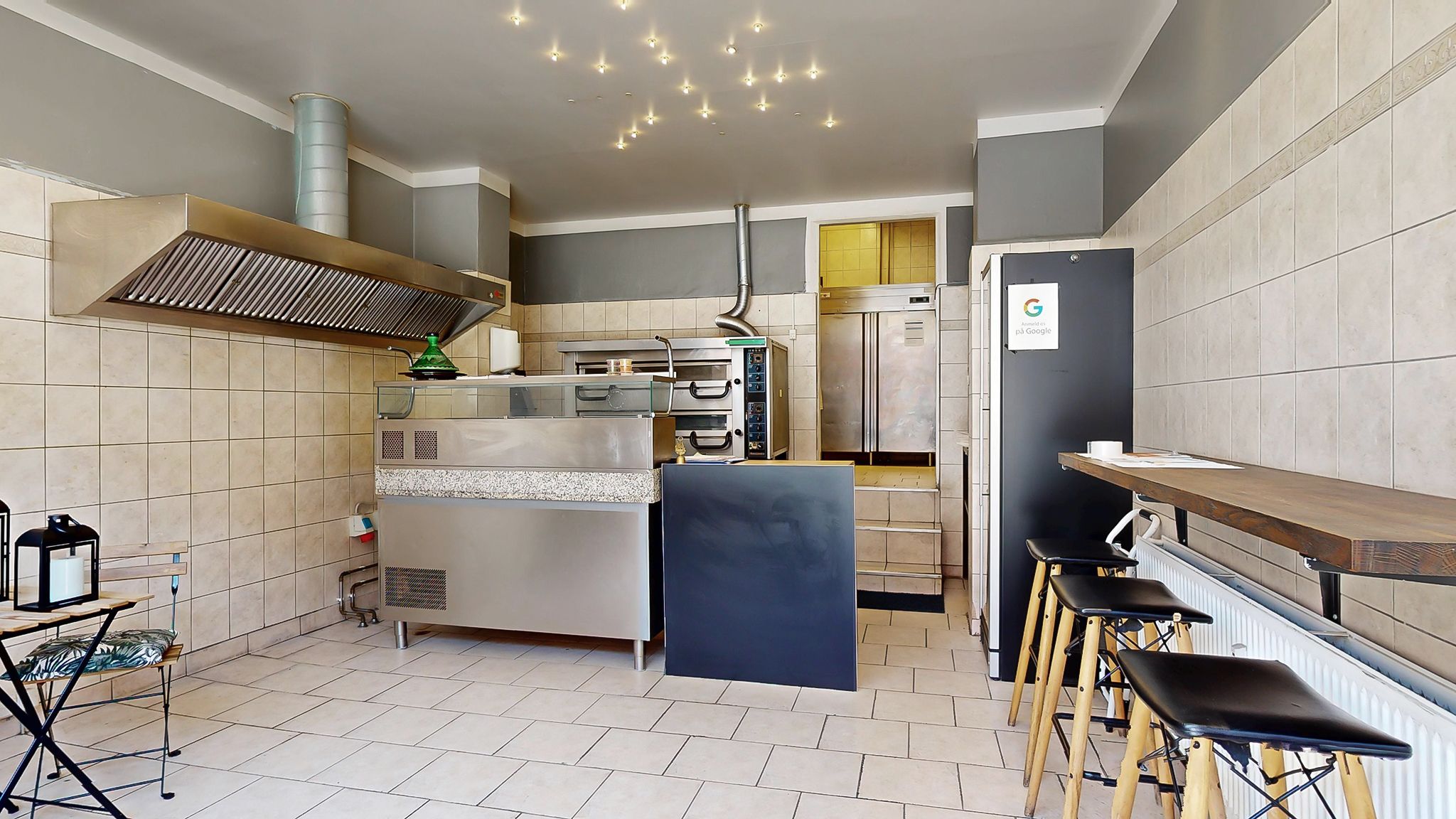 En moderne kommerciel køkken med en stor ovn og flere apparater står klar til at blive overtaget